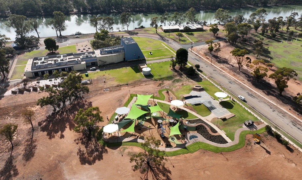 The Ngiwa Kulaithi Robinvale Play Precinct from above. The grey skatepark, green sunshades and play equipment are visible and surrounded by open field, with the Murray River and think bush land visible at the top of the frame.