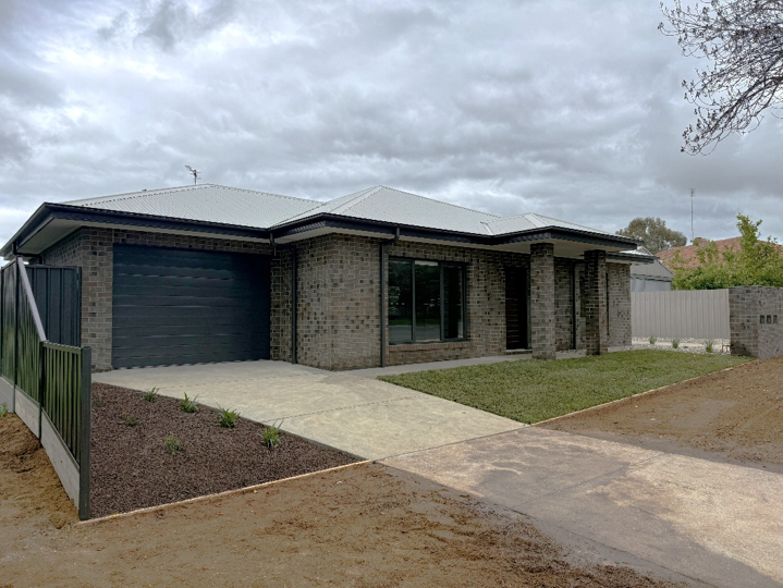 A picture of the front of a new brown-brick house with concrete driveway