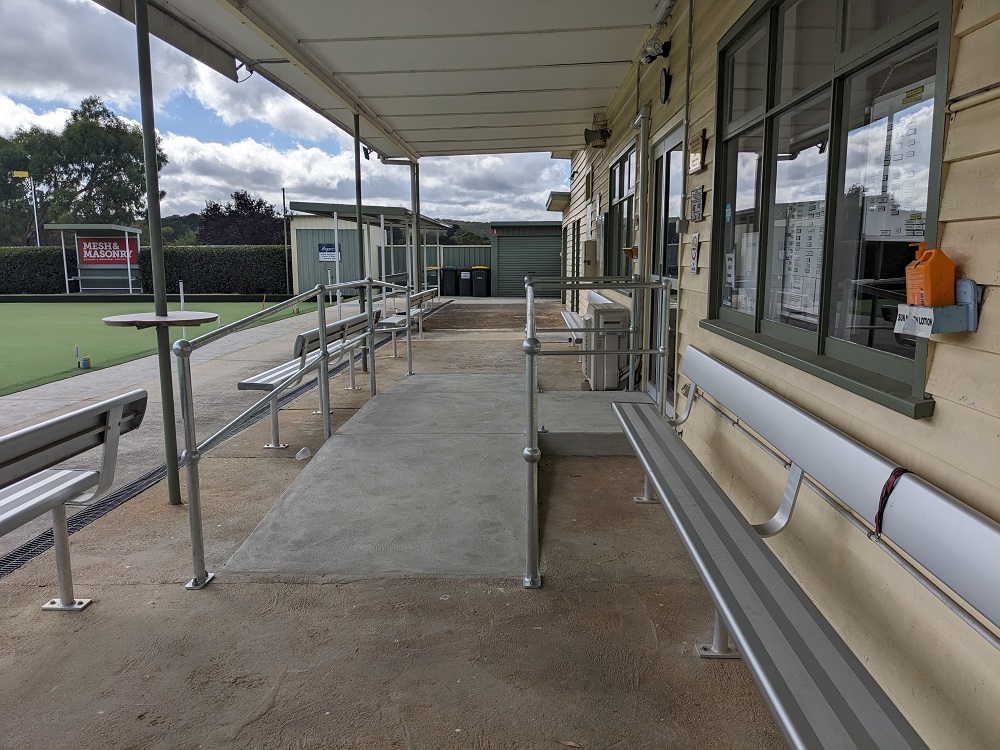 An accessibility ramp that is attached to a building, which is on the right.  