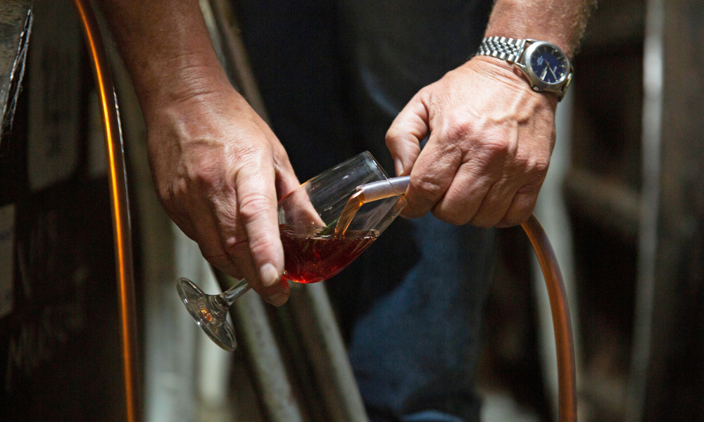 Hand pouring whisky from barrel at Morris of Rutherglen