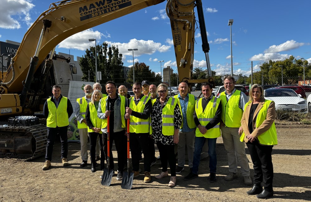 Group of people in hi vis standing in front of escavation machine.