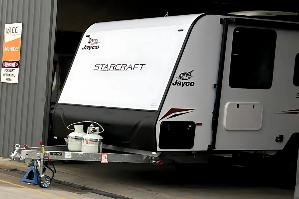 A caravan parked inside a shed with the door open. 