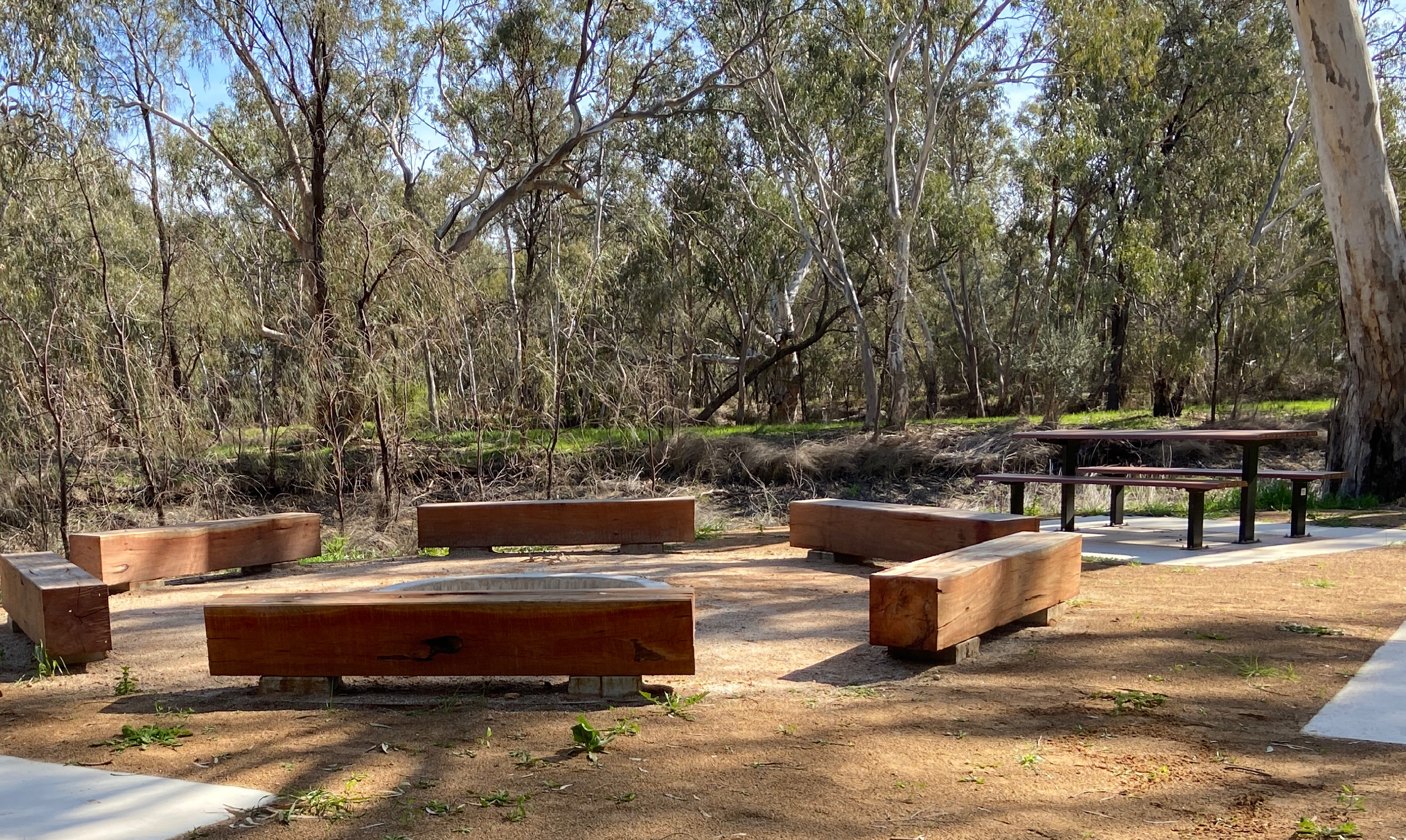 A picture of bench seating and tables near the river