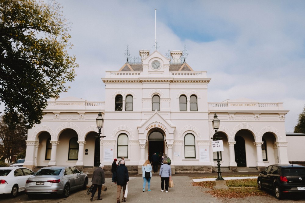 People walking into a white historic town hall building.