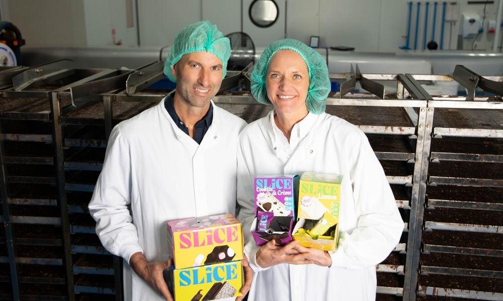 Springhill Farm co-directors James and Fiona Whatley Springhill Farm co-directors James Whatley (L) and Fiona Whatley (R) posing in white lab coats and green hair nets, holding boxes of their ‘Slice’ bars, with baking trays in the background.