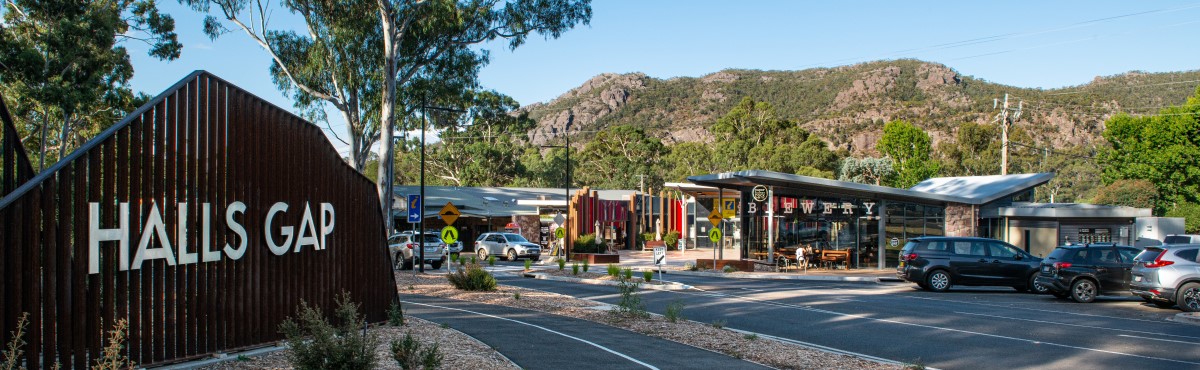 Streetscape in Halls Gap with a large sign welcoming visitors with mountain scenery in the background