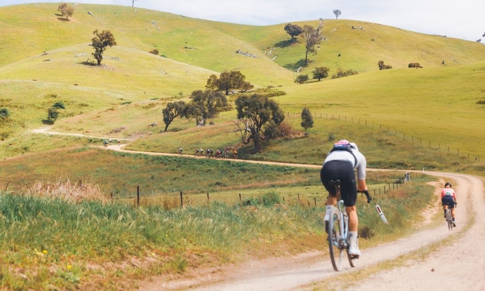 Rider heading up a winding gravel road into the hills of the Goulburn Valley, with gum trees and grass visible on either side of the road.