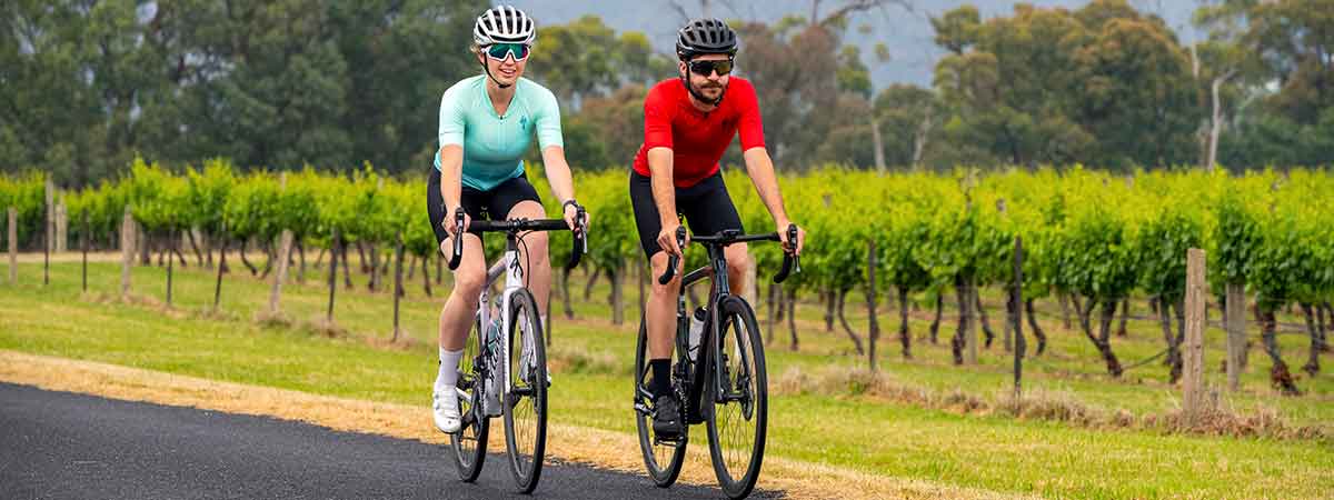Cyclists riding past a vineyard