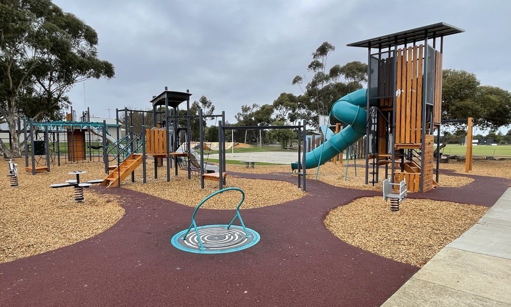 Tambark and rubber floored children's park with multiple structures for swinging, climbing and slides.