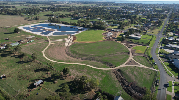 An aerial image of a wetlands, grass, roads and houses.