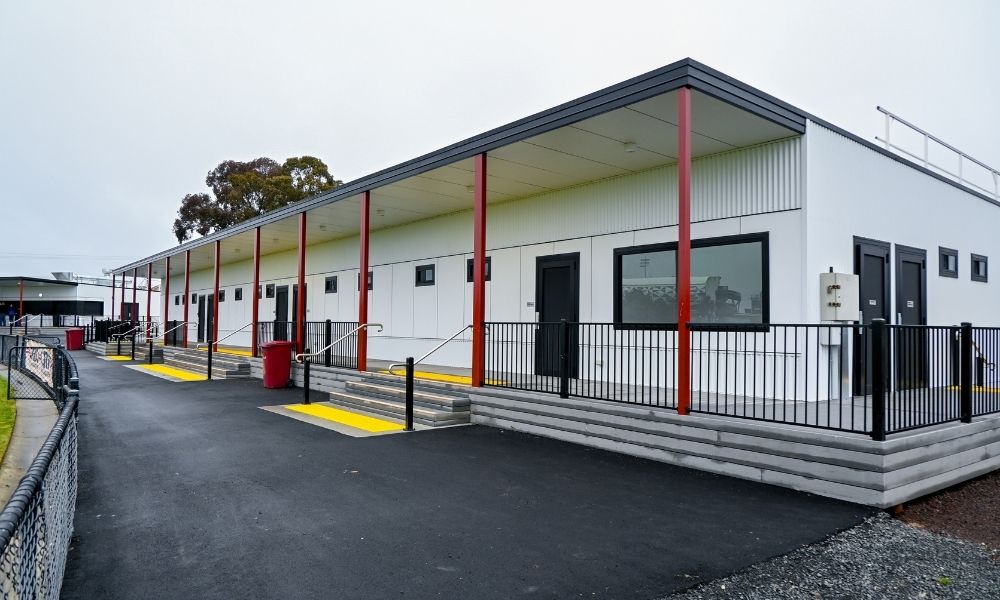 The new Frank Bourke Oval Pavilion, which is white and black, with red veranda beams. There are three small staircase entryways, and the second building is visible to the far left of the frame.
