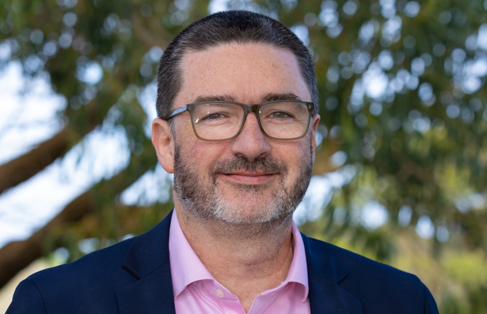 Headshot of Brett Davis - a man with glasses and facial hair.