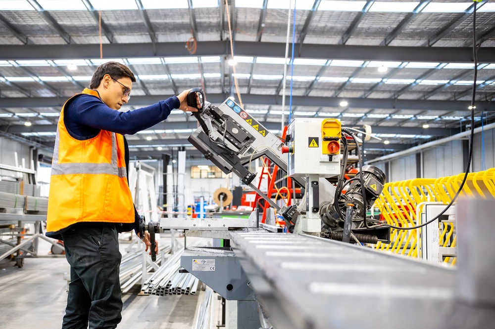 A worker in an orange safety vest using assembly line machinery in JG King's new factory