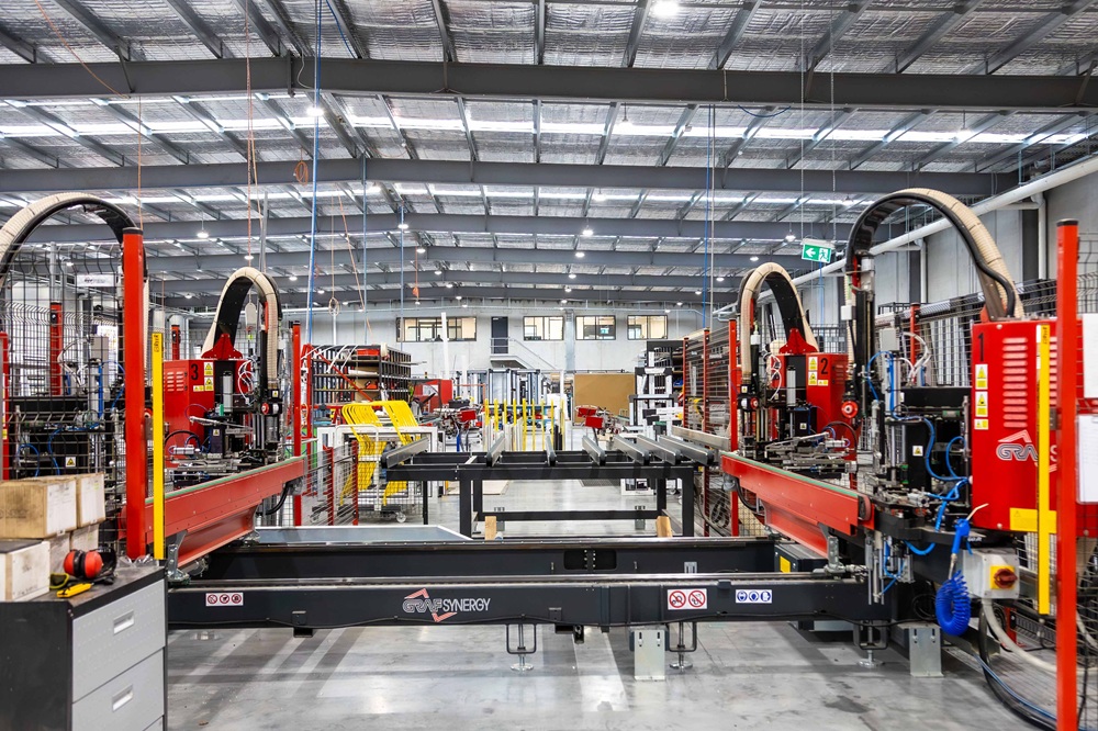 JG King’s new windows and doors assembly line. Black and red machinery is visible, with assembly stations stretching to the back wall of the factory.